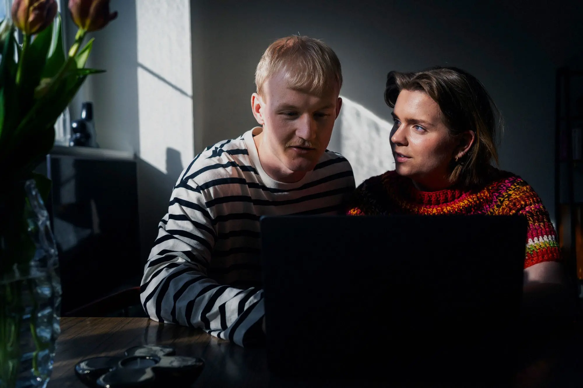 Två personer sitter tillsammans och tittar på en laptop.